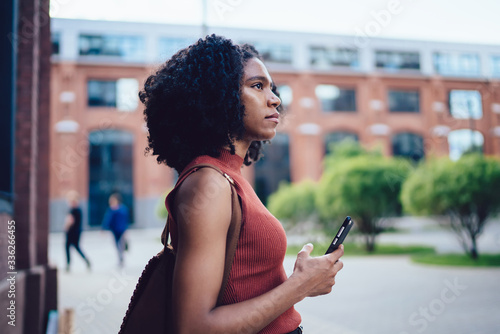 Thoughtful young black woman using cellphone in street