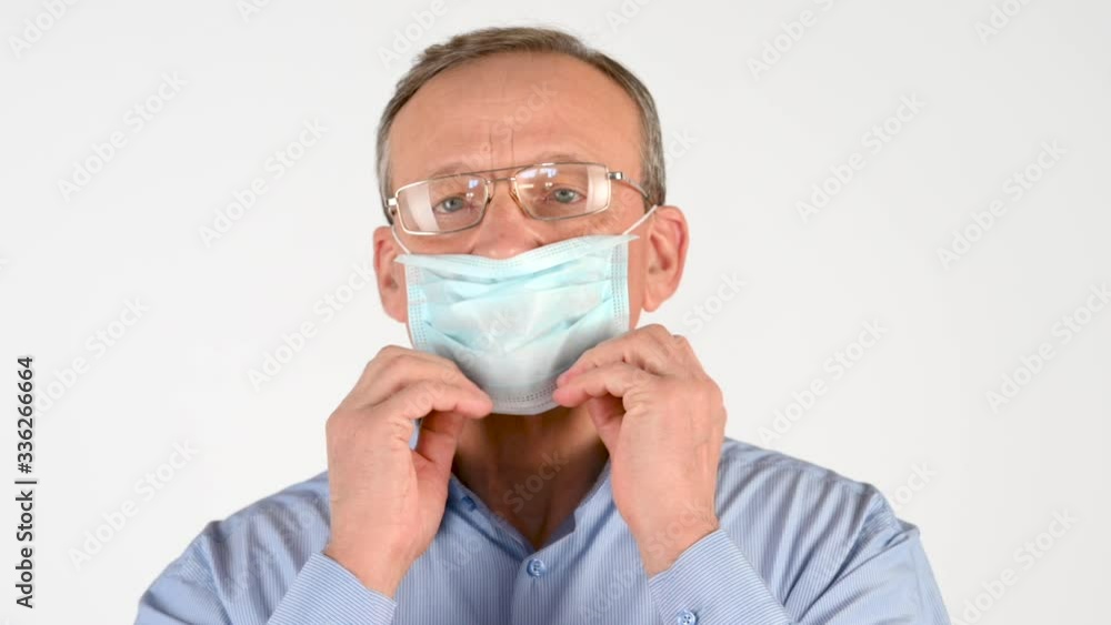 Closeup portrait of an elderly man putting on a medical mask Isolated on a white background. Health care and medical concept. virus protection Closeup portrait of an elderly man putting on a medical mask Isolated on a white background. Health care and medical concept. virus protection