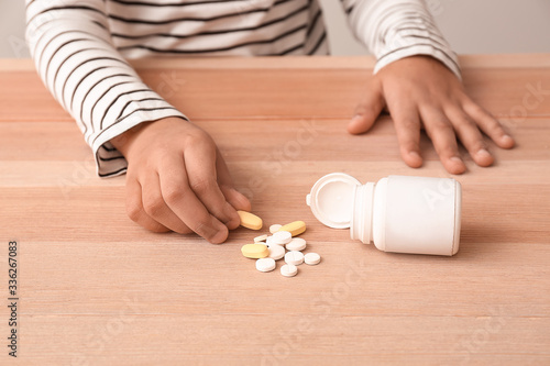 Bild auf Leinwand Little African-American boy with pills at table. Child in danger
