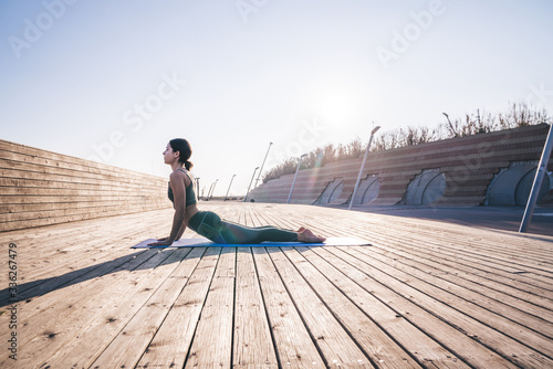 Woman practicing yoga on wooden promenad