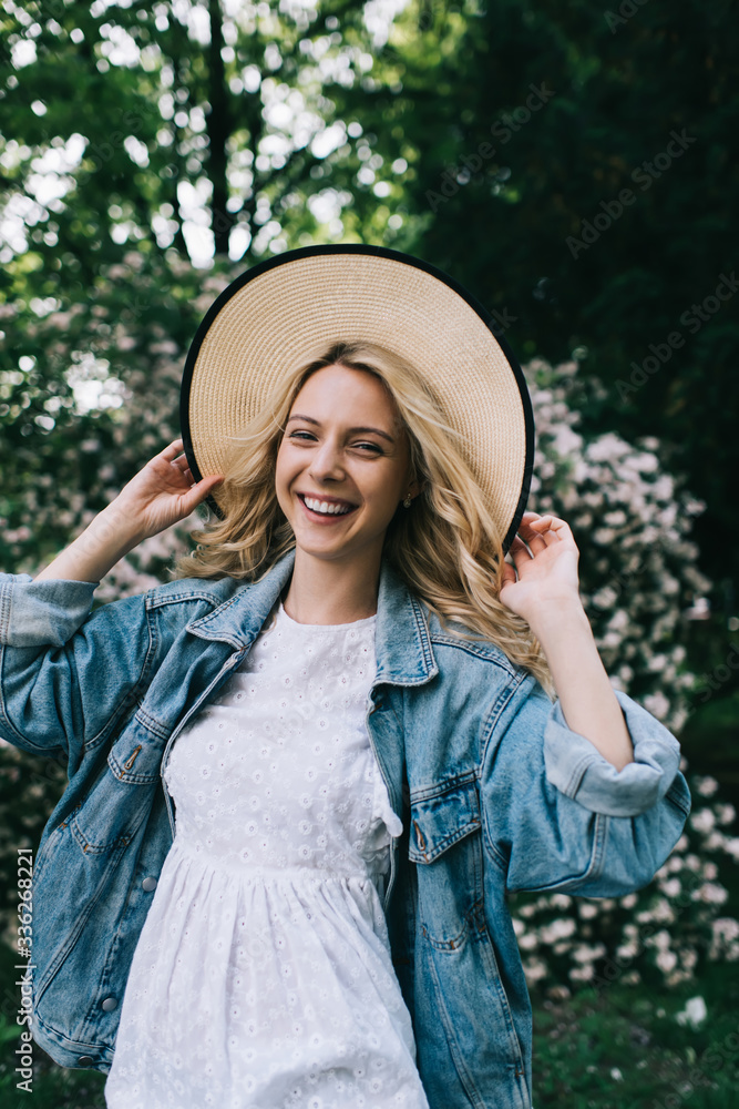 Excited modern woman in hat smiling in garden