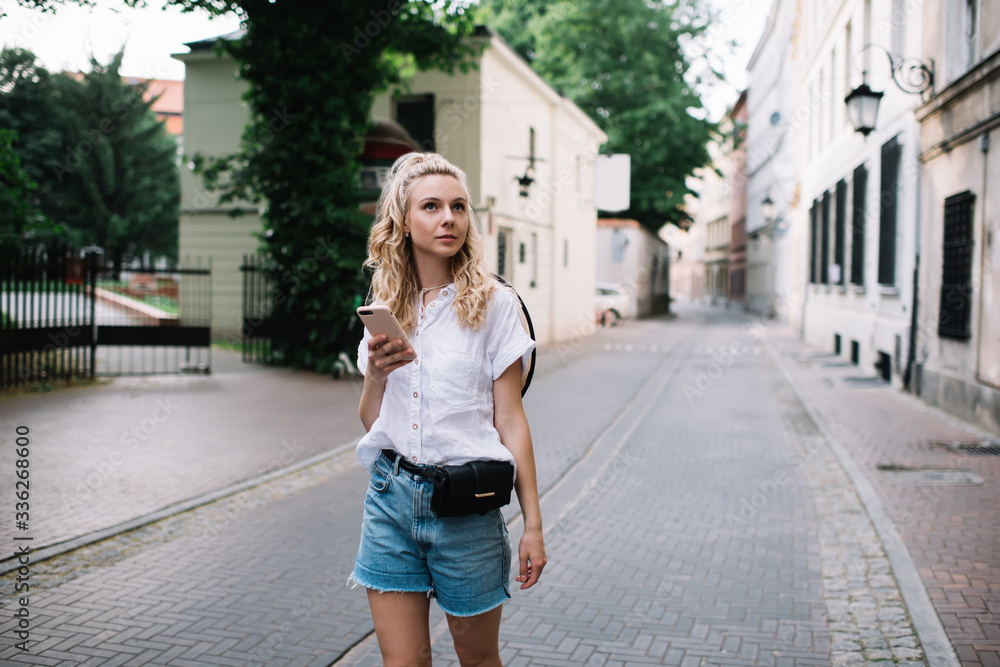 Content female walking on town street in summer