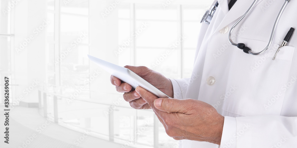 Closeup of a doctor with Tablet Computer medical chart in a modern medical facility. The man is unrecognizable against a high key background. Closeup of a doctor with Tablet Computer medical chart in a modern medical facility. The man is unrecognizable against a high key background.