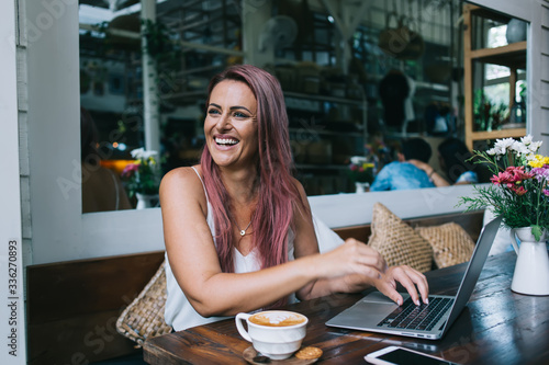Laughing woman with laptop in restaurant