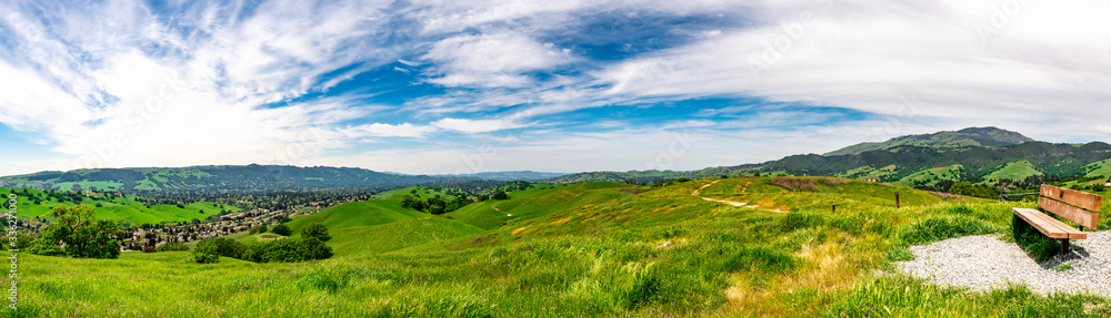 Panoramic view with a park bench overlooking Camino Tassajara on the slope of a hill in Sycamore Valley Preserve Contra Costa County Danville, California.