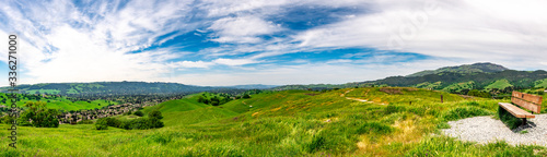 Panoramic view with a park bench overlooking Camino Tassajara on the slope of a hill in Sycamore Valley Preserve Contra Costa County Danville, California.