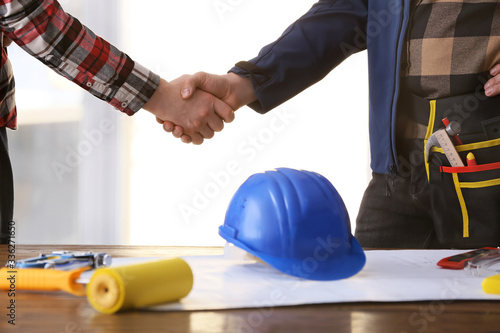 Male builders shaking hands in office