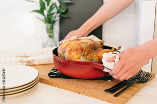 Hot and fresh oven-roasted whole chicken with lemon and garlic in a red dutch oven photo