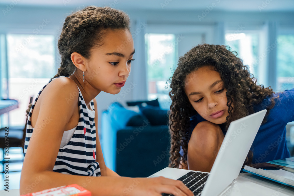 Sisters working together on laptop computer Sisters working together on laptop computer