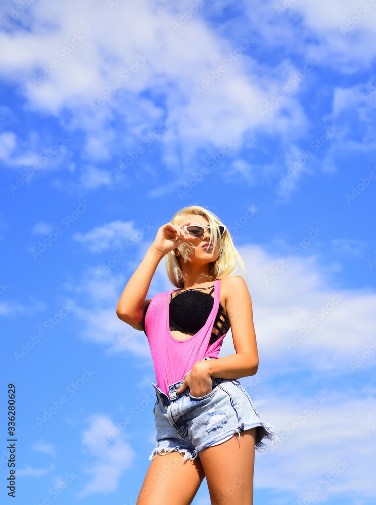 Fashion woman posing over blue sky. Beautiful girl posing on sky background in the hot sun, outdoor portrait. Young blonde beauty woman. Fashion woman posing over blue sky. Beautiful girl posing on sky background in the hot sun, outdoor portrait. Young blonde beauty woman.
