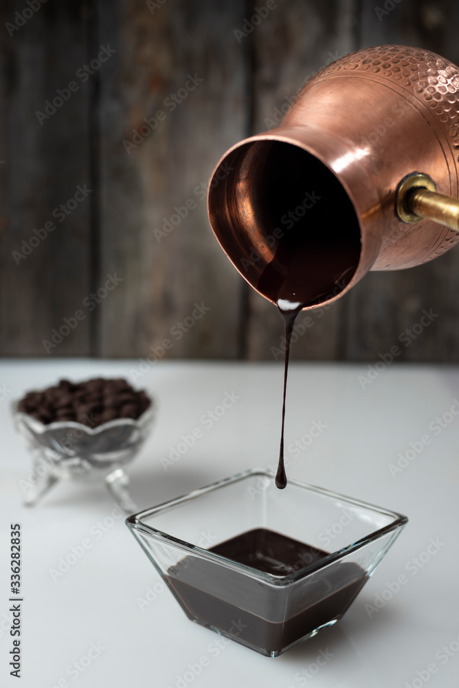 chocolate derretido tirado sobre marmol con una jarra antigua de cobre 