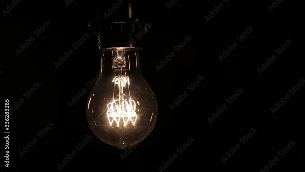 Close-up of the Edison lamp with warm light sways lightly on a black background Close-up of the Edison lamp with warm light sways lightly on a black background