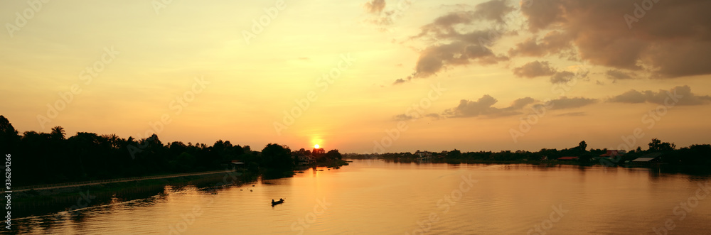Beautiful sunset above rural river view with fisherman riding boat