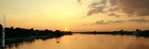 Beautiful sunset above rural river view with fisherman riding boat © bongkarn