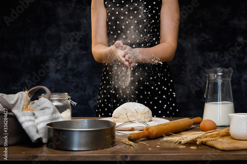 The confectioner prepares the dough, bread, cakes. Preparation and work with flour, eggs, milk and ingredients. Delicious food, recipes, cooking, gastronomy, on a dark background and wooden table.
