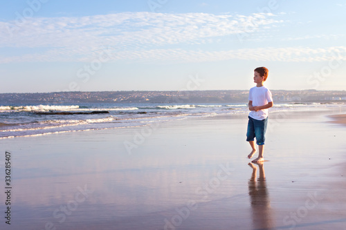 Young boy on the beach looking at the ocean