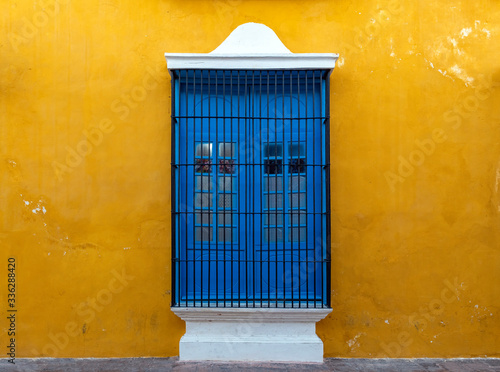 A blue window on a yellow wall, a colorful facade in the historic city center of Campeche, Yucatan Peninsula, Mexico.