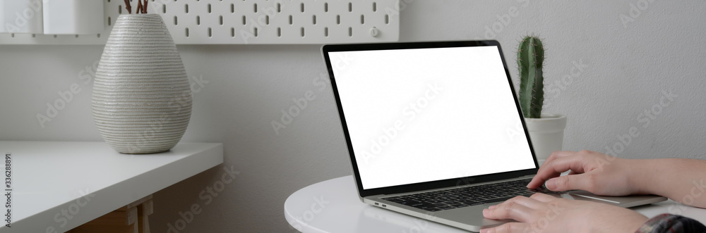 Cropped shot of female freelancer working on blank screen laptop on white circle table - obrazy, fototapety, plakaty 
