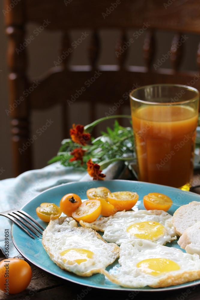 sunny breakfast life style, fried eggs and yellow cherry tomatoes. on a blue plate. yellow and blue