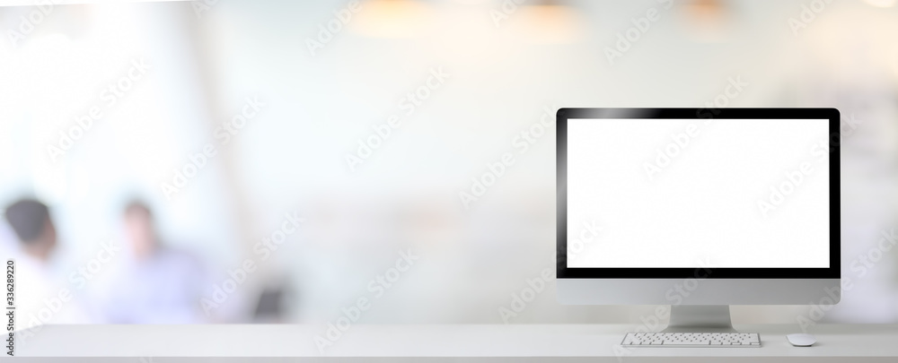 Close up view of blank screen computer and copy space on white table in blurred office room background Close up view of blank screen computer and copy space on white table in blurred office room background