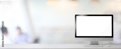 Close up view of blank screen computer and copy space on white table in blurred office room background