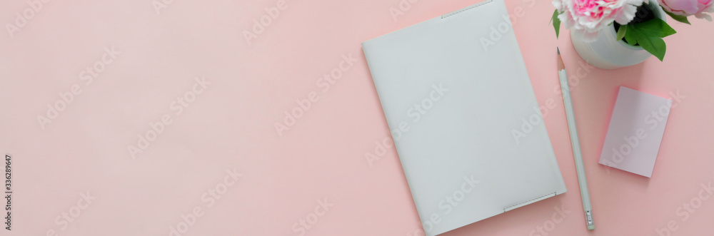 Top view of creative home office with diary notebook on pink table Top view of creative home office with diary notebook on pink table