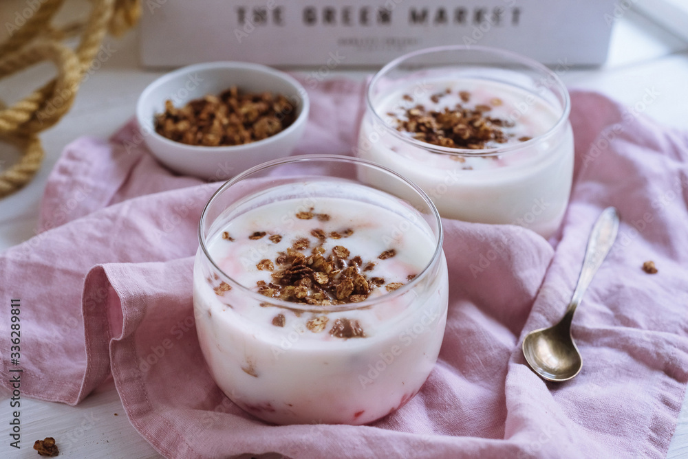 Bowl of granola with natural yogurt and raspberries. On a white wooden background and a pink fabric napkin. Copper spoon. Bowl of granola with natural yogurt and raspberries. On a white wooden background and a pink fabric napkin. Copper spoon.