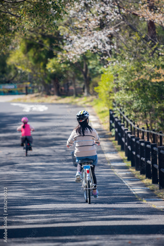 春の公園で自転車を乗っている子供姉妹二人