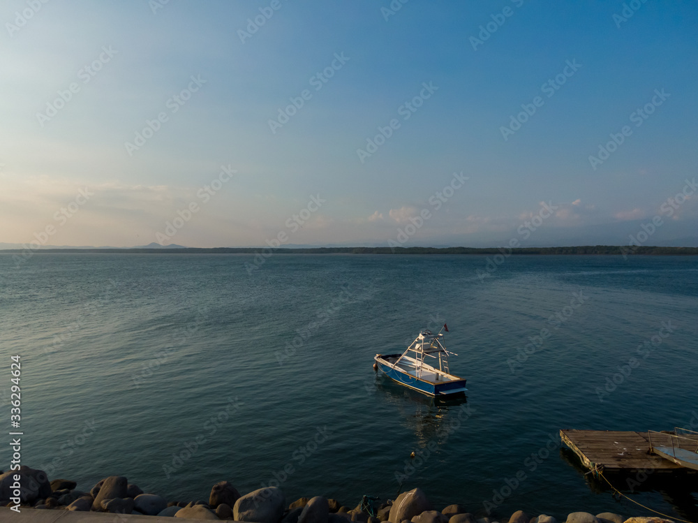 Beautiful landscape view of a boat in calm waters of the ocean near to a pier