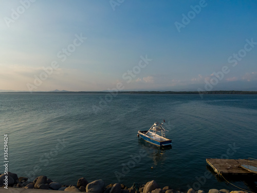 Beautiful landscape view of a boat in calm waters of the ocean near to a pier © Gian