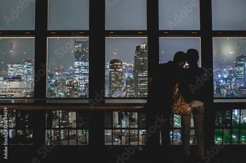Couple and panoramic view of Tokyo skyline by night from the Tokyo Tower Observation Deck, Japan