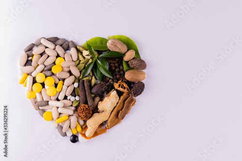 Top view of herbal medicines with spices and herbs in a heart shape on white background with copy space. Ayurvedic medicines for heart diseases concept photo