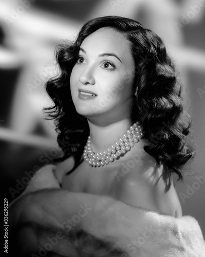 Beautiful young woman wearing luxury fur coat and pearls. image in black and white conversion