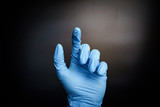 Human hands in blue surgical gloves by gesture one finger hands isolated black background with a medium shot
