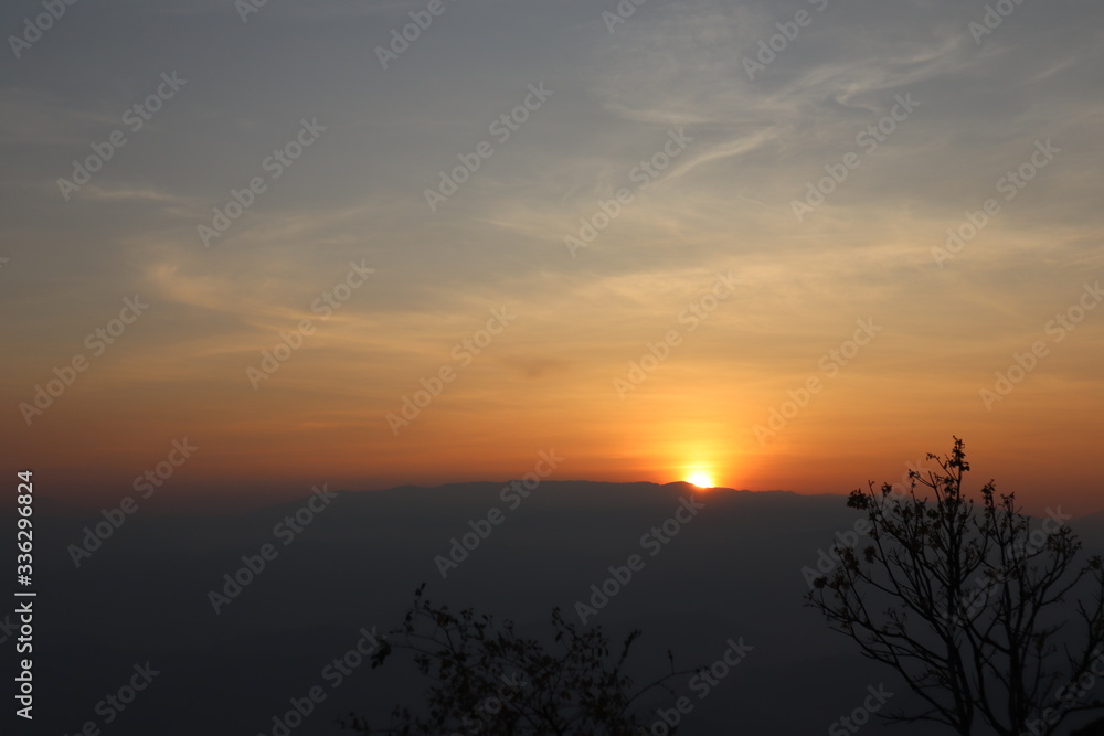 The rising sun from the back of the mountain. The golden light sparks all over the sky. Beautiful natural scenery pictures.
