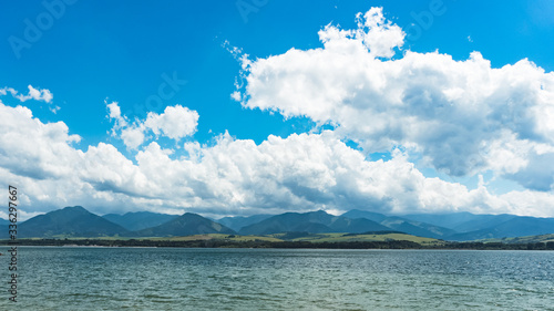 Bright bue sky with large fluffy clouds above the lake. Mountains in the background. Liptovska Mara, Slovakia photo