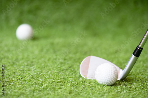 Selective golf club and golf ball on green grass background.Iron golf club hitting ball into a hole.Outdoor sport.