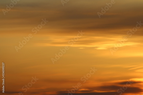 Sun below the horizon and clouds in the fiery dramatic orange sky at sunset or dawn backlit by the sun. Place for text and design. © Stanislav