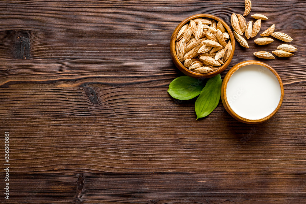 Alternative milk made from almond. Drink near unpeeled on dark wooden table top-down copy space Alternative milk made from almond. Drink near unpeeled on dark wooden table top-down copy space