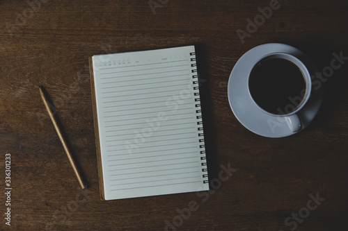 Notebook with coffee and pencil on wood table for writing at home. Work at home concept.