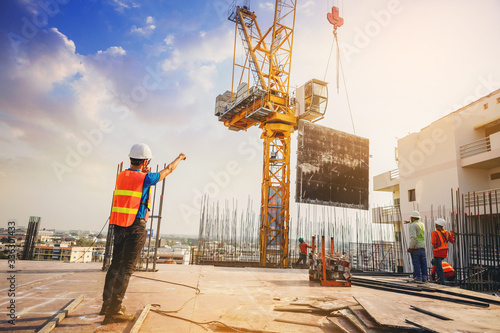 Structural engineer and architect working with building crane transfer control at the outdoors construction site.