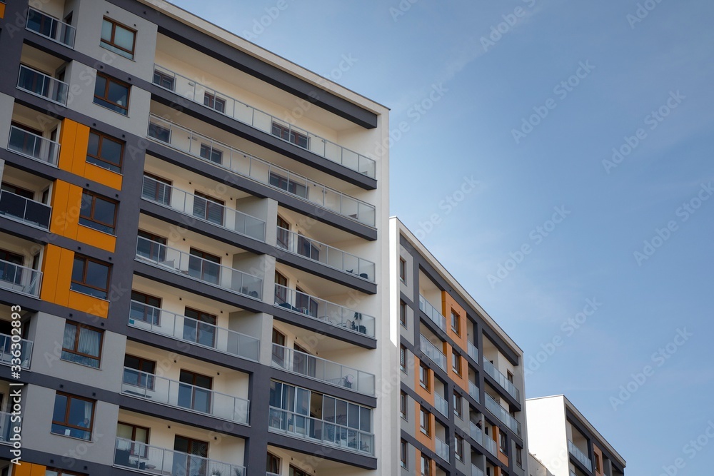 Fototapeta premium Exterior of new apartment buildings on a blue cloudy sky background. No people. Real estate business concept.