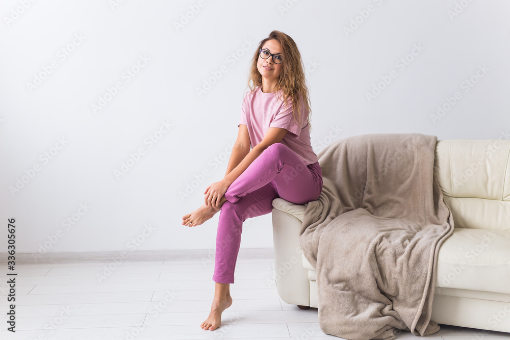 Young attractive woman dressed in beautiful colorful pajama posing as a model in her living room. Comfortable sleepwear, home relaxation and female fashion concept.