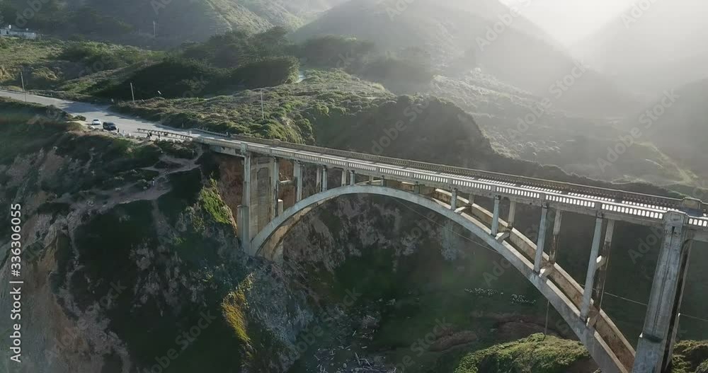Aerial view Descending shot, stunning view of Bixby Creek Bridge, Cross Canyon Sunset in the background. Aerial view Descending shot, stunning view of Bixby Creek Bridge, Cross Canyon Sunset in the background.