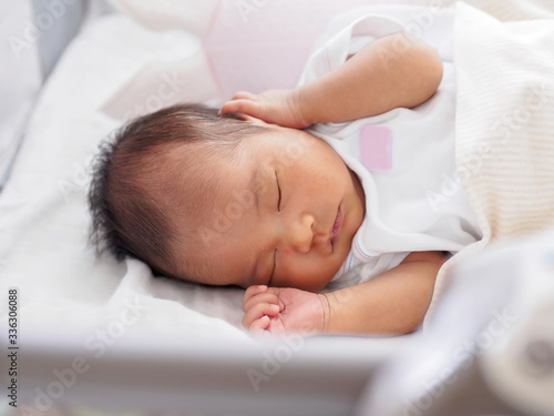 Portrait of a newborn baby girl who sleeps happily, comfortable, safe, and is well looked after by her parents.