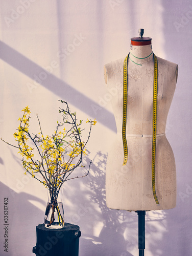 tailor's mannequin in the workshop on a bright background with flowers photo