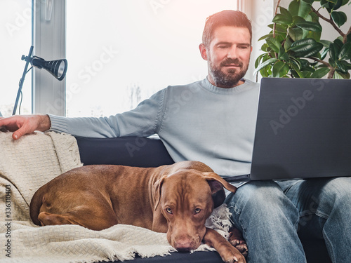 Handsome man and a charming puppy. Working From Home. Close-up, indoors. Studio photo, white color. Concept of care, education, obedience training and raising pets