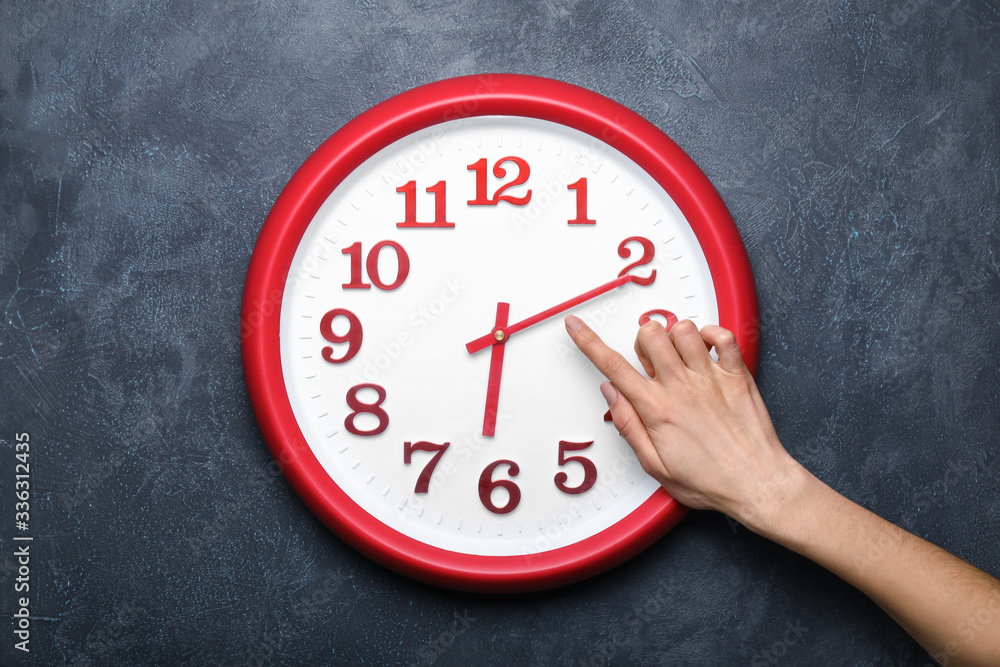 Female hand with clock on dark background. Time management concept Female hand with clock on dark background. Time management concept