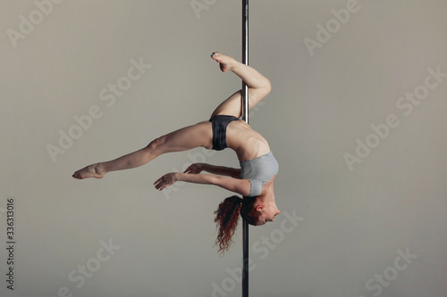 Beautiful sports girl doing acrobatics on a pole