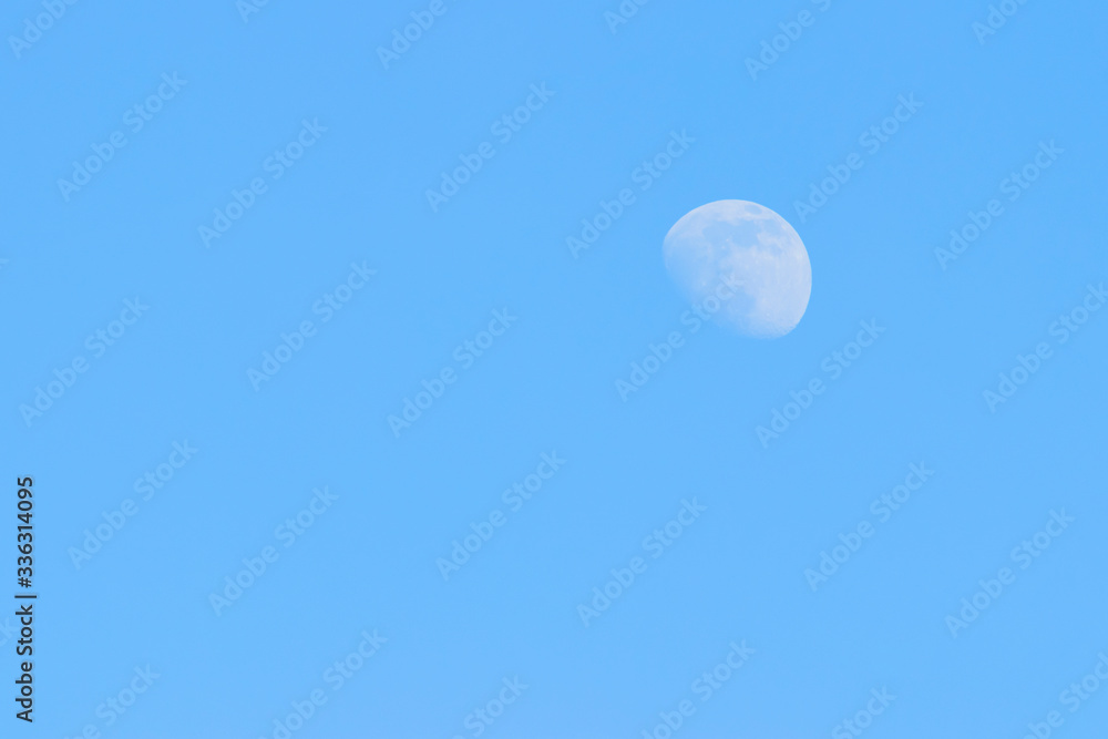 Siberia, April 2020. Photo of the moon in the daytime, in the blue sky, illuminated by the sun. Siberia, April 2020. Photo of the moon in the daytime, in the blue sky, illuminated by the sun.